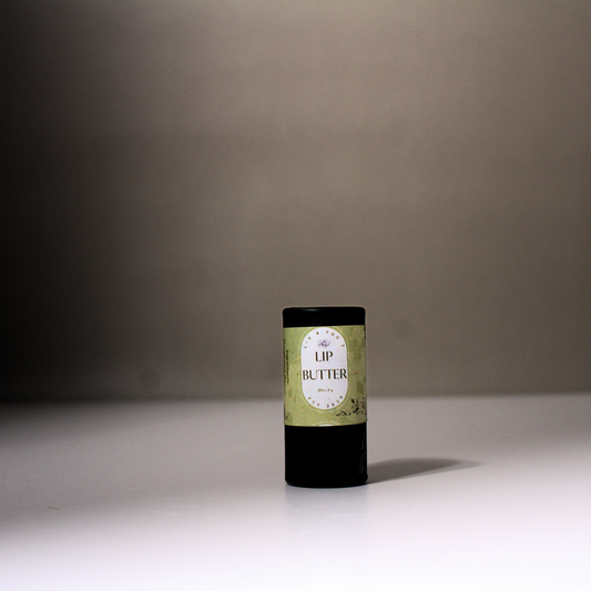 Lip Butter in black cardboard tube with green and white label and black writing on white table