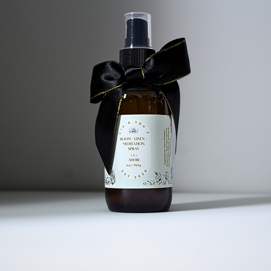 Room spray in brown glass bottle with black and gold bow with white label and black writing for Liv 4 You 2