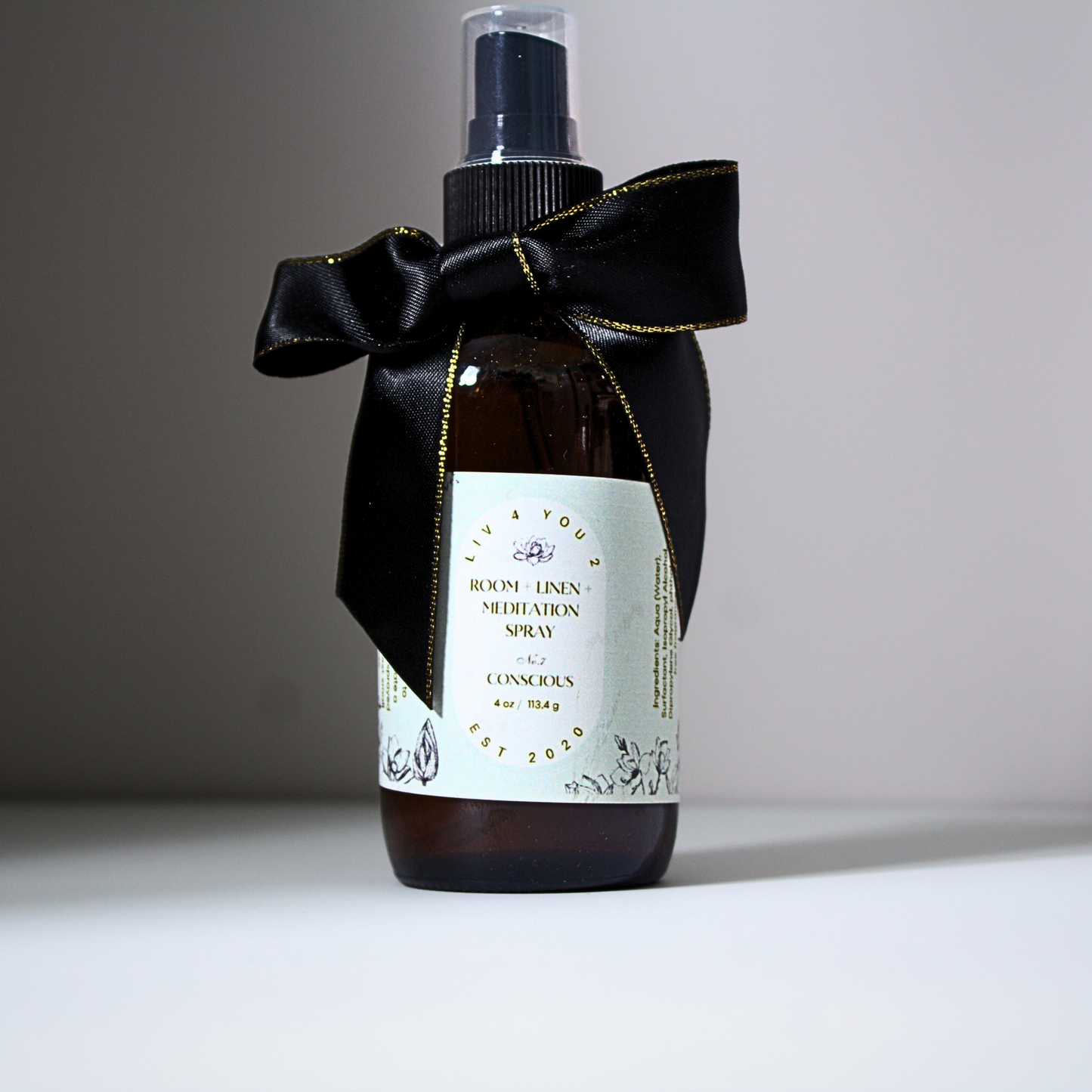 Room spray in brown glass bottle with black and gold bow with white label and black writing for Liv 4 You 2