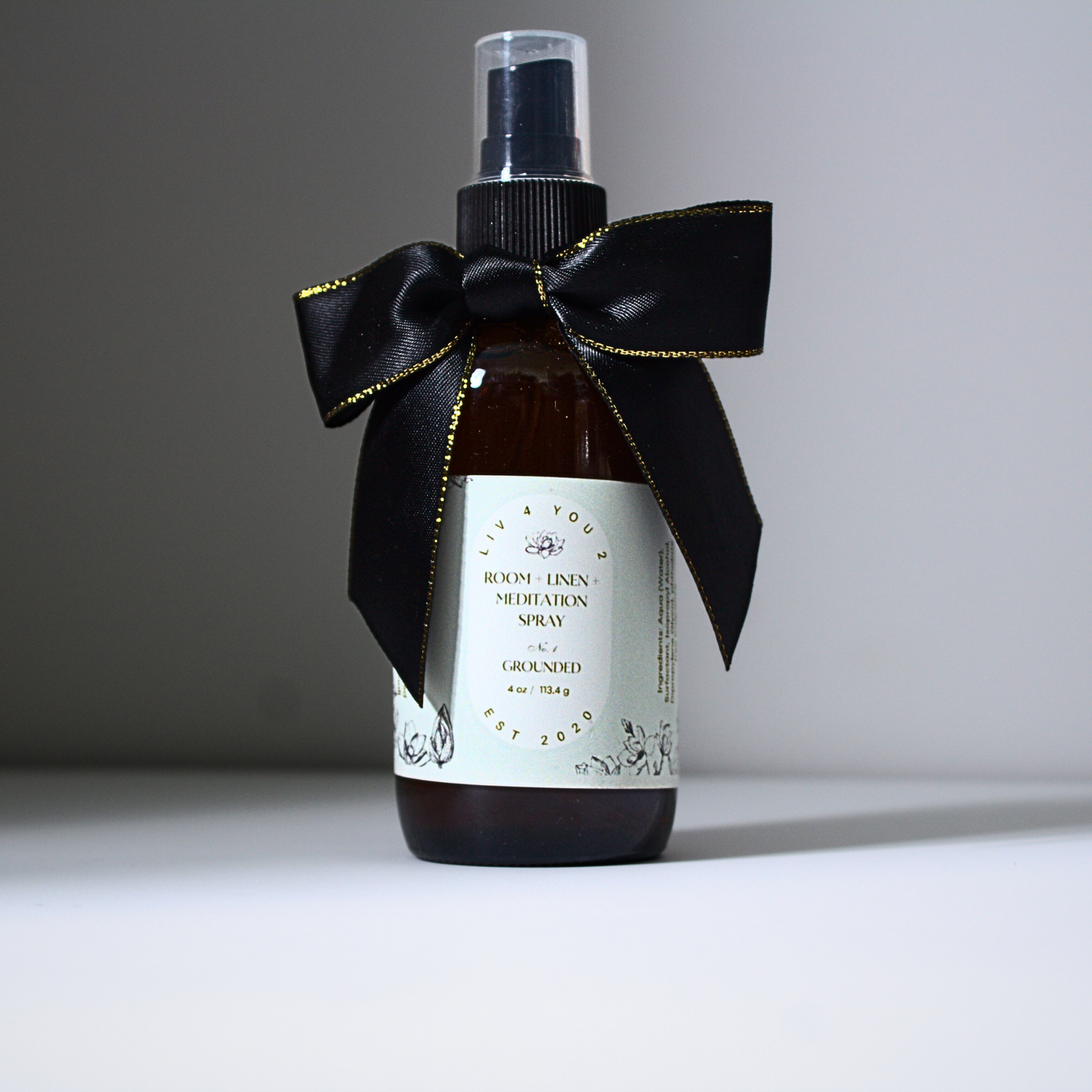 Room spray in brown glass bottle with black and gold bow with white label and black writing for Liv 4 You 2