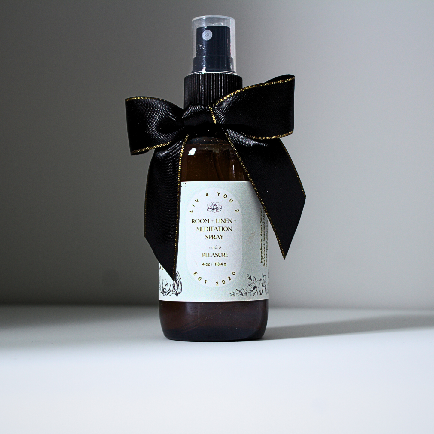 Room spray in brown glass bottle with black and gold bow with white label and black writing for Liv 4 You 2