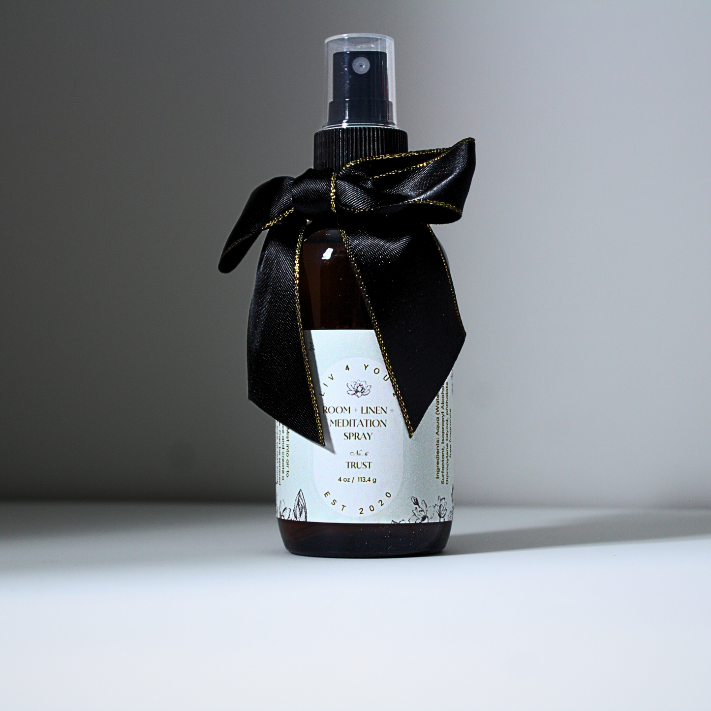 Room spray in brown glass bottle with black and gold bow with white label and black writing for Liv 4 You 2